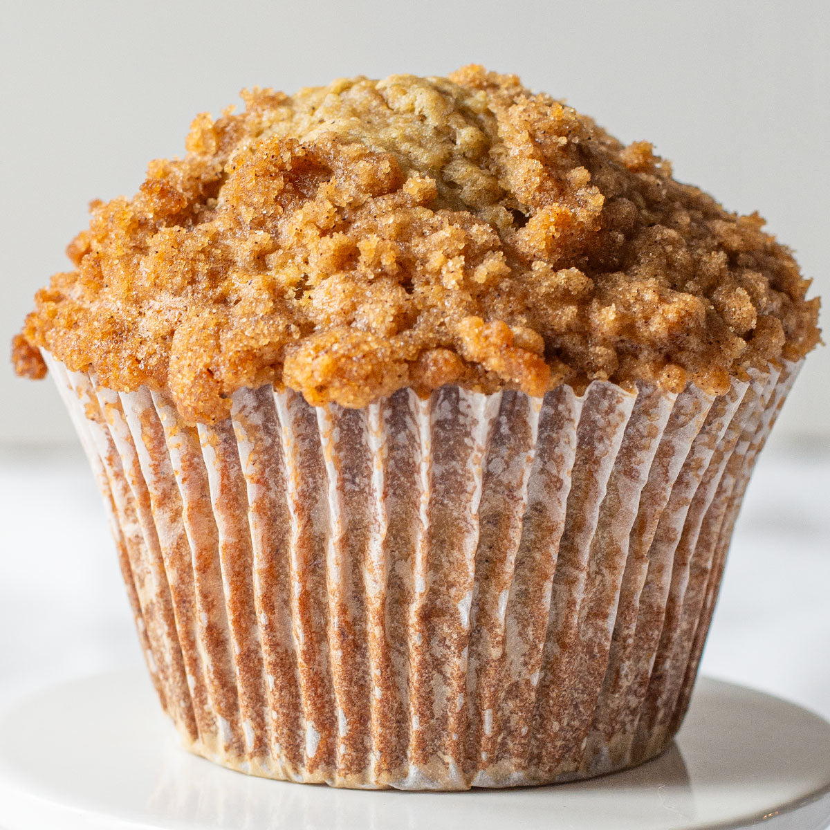 A scrumptious image of a Jumbo Banana Crumb Muffin, highlighting its moist banana-infused base and mouthwatering crumb topping made with brown sugar and cinnamon.
