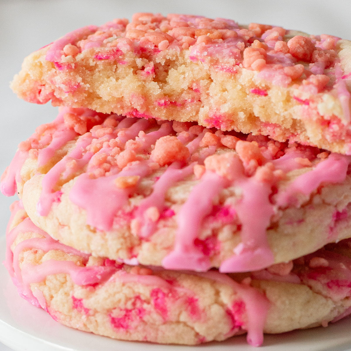 A fun and colorful image of a Bubble Gum Delight Cookie, showcasing its soft sugar cookie base with vibrant pink sprinkles mixed in, topped with a pink bubble gum flavored glaze and sprinkled with bubble gum flavored dessert crumbs.