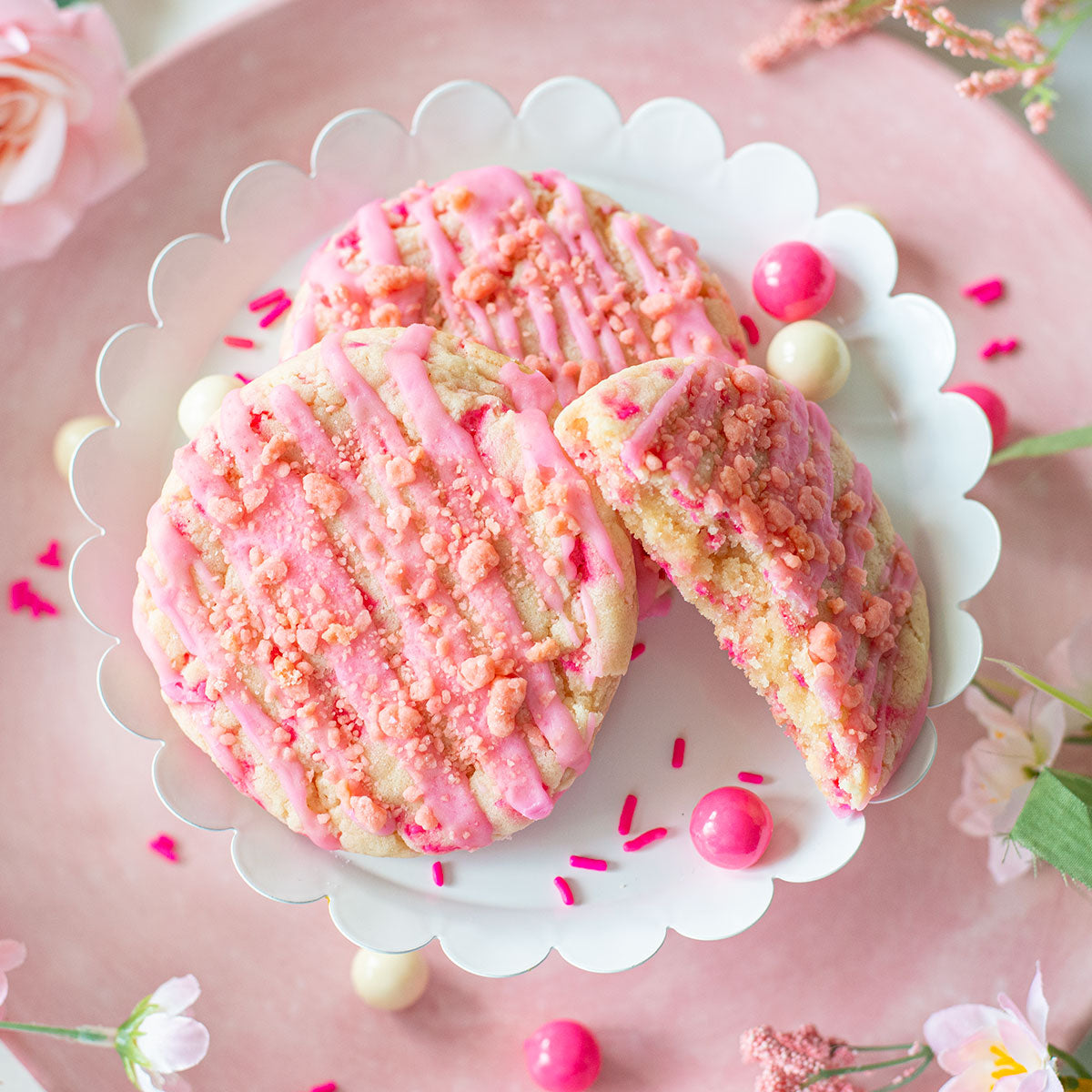 A playful assortment of Bubble Gum Delight Cookies, featuring their eye-catching appearance with the cookie base adorned in pink sprinkles and a pink bubble gum flavored glaze, providing a whimsical and nostalgic treat.
