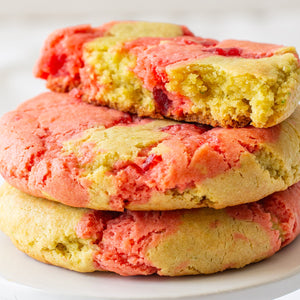 A stack of 3 Cherry Limeade Cookies, with one cookie broken in half to reveal the vibrant swirled interior of cherry and lime dough.