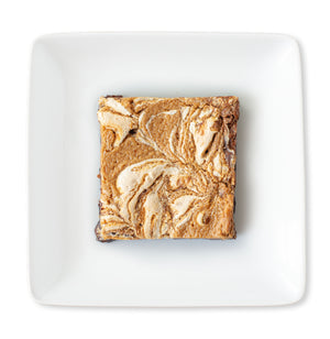 A close-up image of a Fluffernutter Brownie with visible layers of rich chocolate brownie, peanut butter filling, and marshmallow creme.