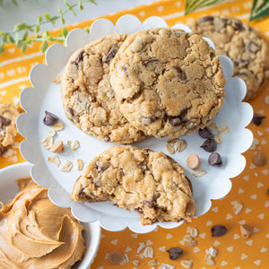 Cookies with chocolate chips, peanut butter chips, oats and peanut butter on a decorative plate with a yellow background.