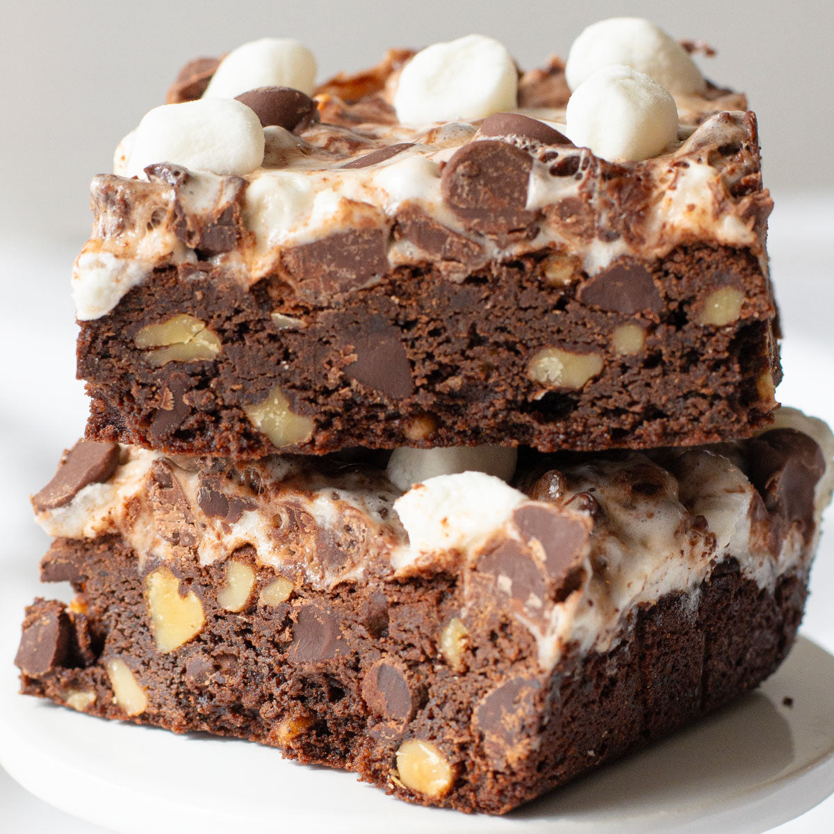 A close-up image of a fudgy Rocky Road Brownie with toasted walnuts and a gooey mixture of marshmallows and chocolate chips on top.