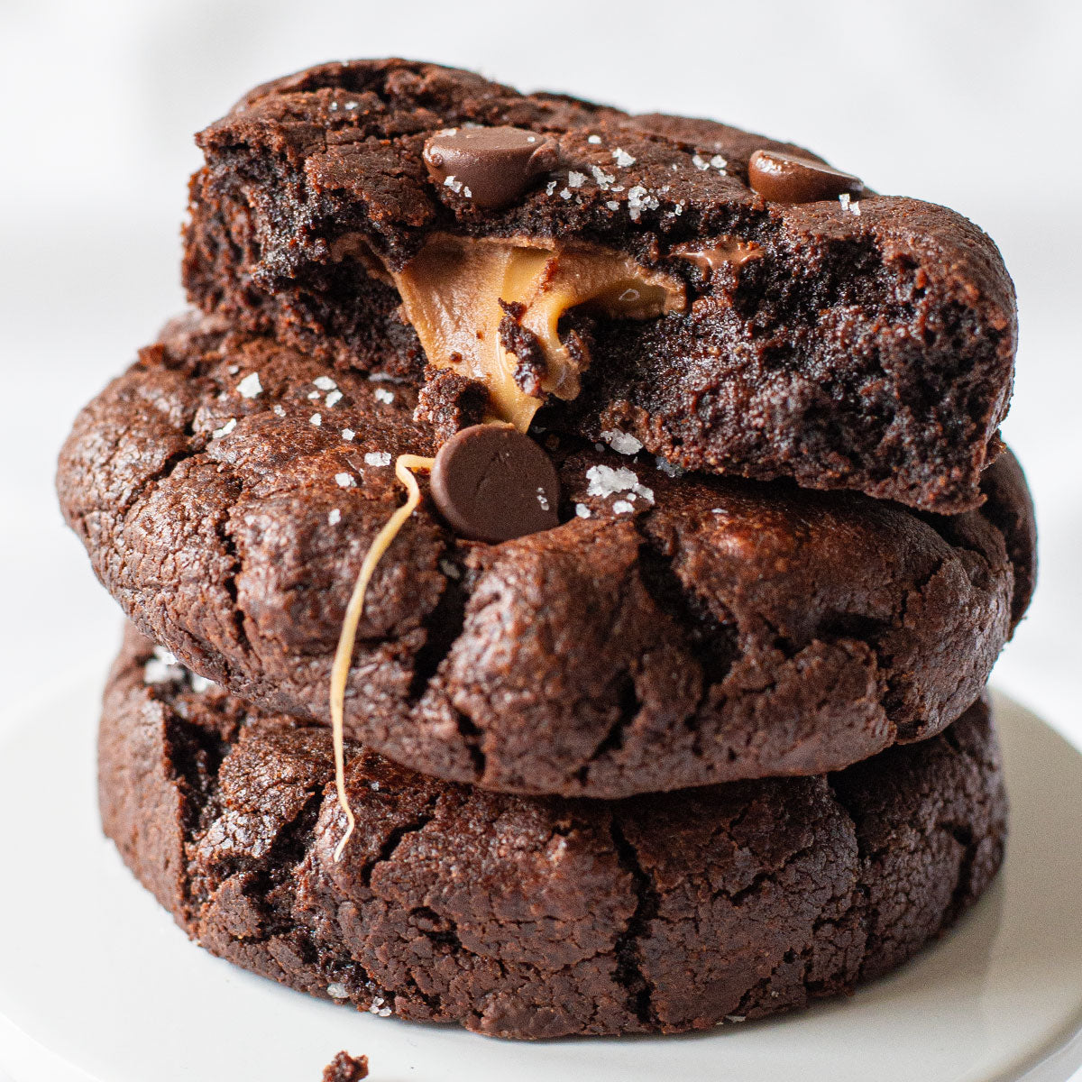 A delectable image of a Salted Caramel Cookie, showcasing its rich chocolate cookie dough wrapped around a caramel-filled candy, and topped with a sprinkle of fleur de sel for the perfect sweet and salty balance.