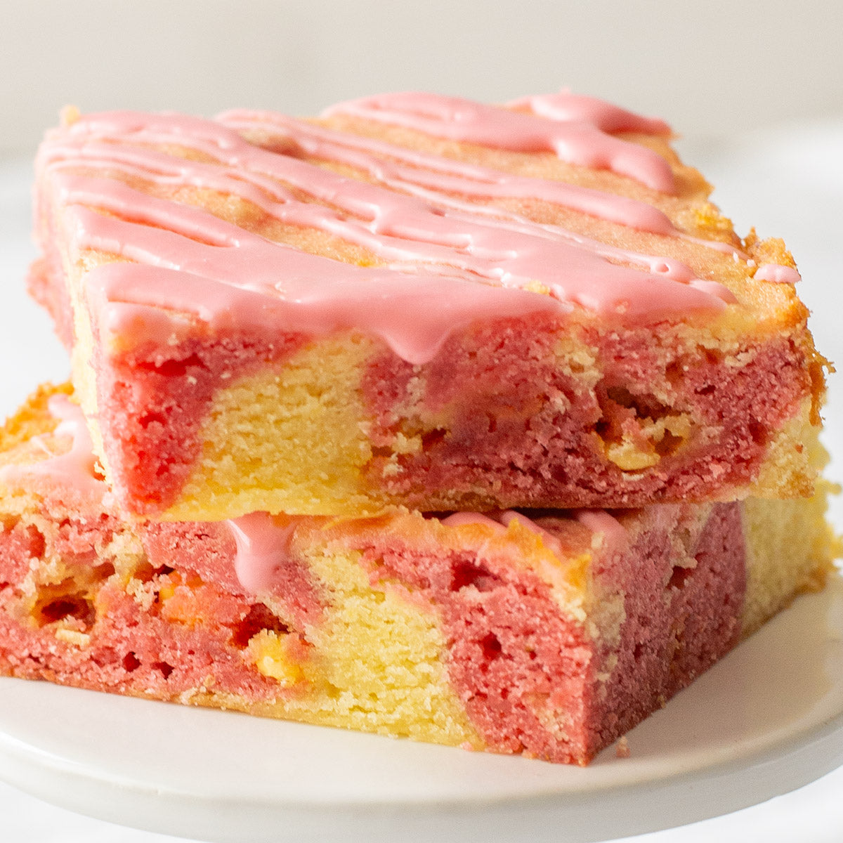 A delectable strawberry lemon blondie showcasing swirls of lemon and strawberry dough, dotted with lemon baking chips, and glazed with a vibrant strawberry topping, promising a harmonious blend of citrus and berry flavors in every slice.